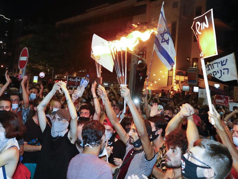 Israelis wearing protective face masks due to the COVID-19 coronavirus pandemic, take part in a demonstration on July 18, 2020, in Charles Clore Park in the Israeli coastal city of Tel Aviv to protest against the Israeli government and Prime Minister Benjamin Netanyahu for the broken promises made by the Israeli government during the Covid-19 pandemic. Israel's government said today it was imposing new restrictions to limit the spiraling spread of coronavirus.