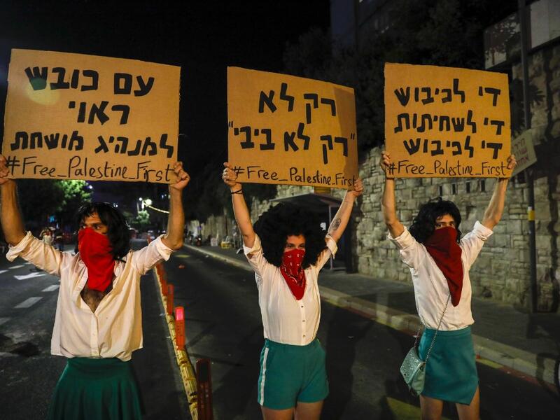 Israeli demonstrators lift placards during a rally against Prime Minister Benjamin Netanyahu outside his official residence in Jerusalem, on July 18, 2020, amid the coronavirus pandemic. Israeli police fired water cannons to disperse anti-government protests attended by thousands on Saturday, as public anger mounts over the handling of the coronavirus crisis. 