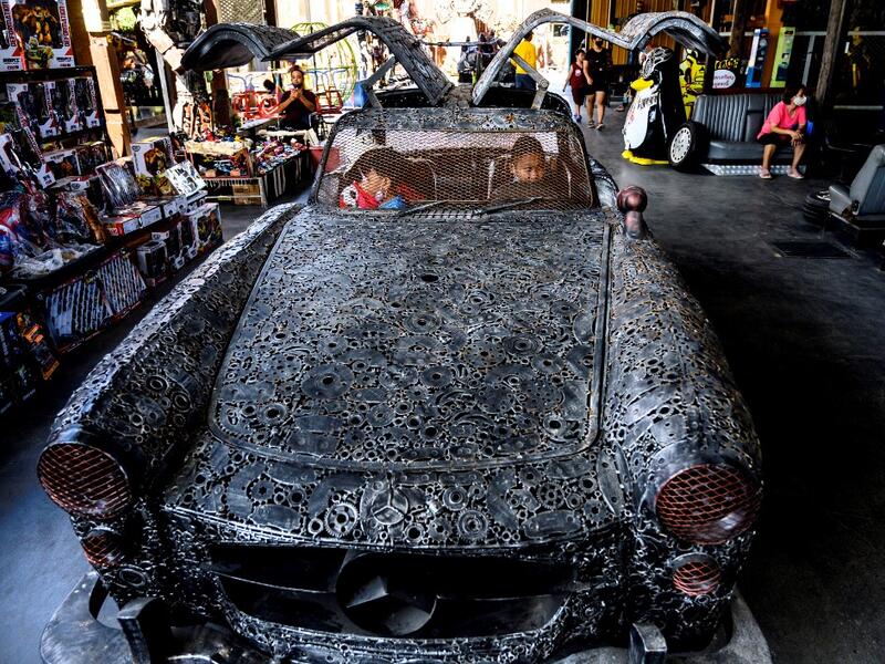 This photograph taken on July 18, 2020 shows children playing in a car made of scrap metal parts at the Ban Hun Lek museum in Ang Thong, some 100km north of Bangkok. "Ban Hun Lek" or "The House of Steel Robots" is a museum where a collective of artists display their scrap metal creations depicting popular comics and sci-fi film characters. Mladen ANTONOV / AFP