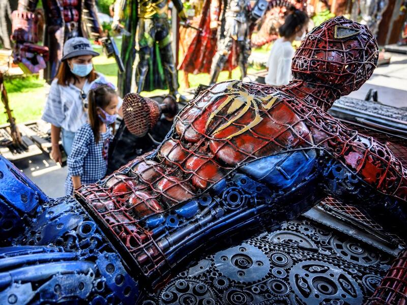 This photograph taken on July 18, 2020 shows tourists looking at a life-sized Spiderman sculpture made of scrap metal parts at the Ban Hun Lek museum in Ang Thong, some 100km north of Bangkok. "Ban Hun Lek" or "The House of Steel Robots" is a museum where a collective of artists display their scrap metal creations depicting popular comics and sci-fi film characters. Mladen ANTONOV / AFP