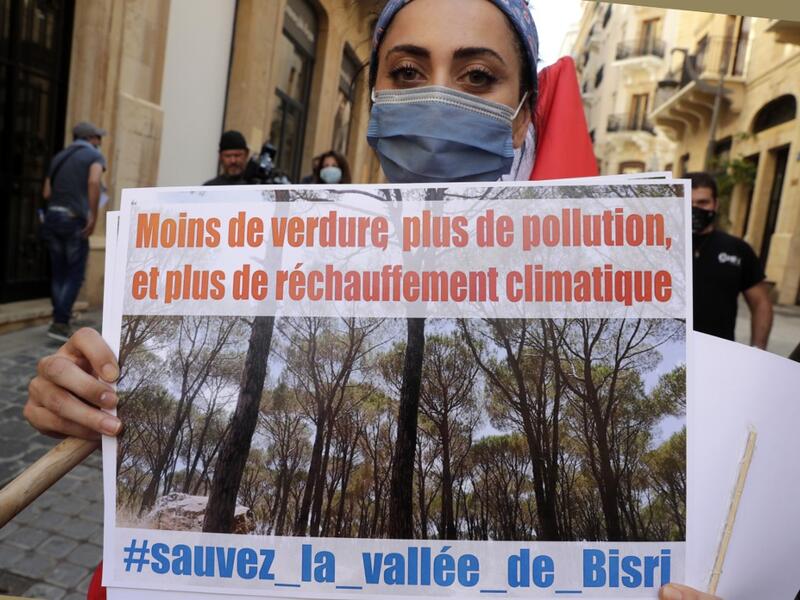 A demonstrator holds a placard as tshe takes part in a rally in front of the World Bank offices in the downtown district of the Lebanese capital Beirut on July 25, 2020, to protest against the Bisri dam project, partly financed by the World Bank. The government says the Bisri dam is vital to tackling chronic water shortages. But activists say it will ravage most of the region's farmland and historic sites, and they also fear the consequences of building it on a seismic fault line.  ANWAR AMRO / AFP