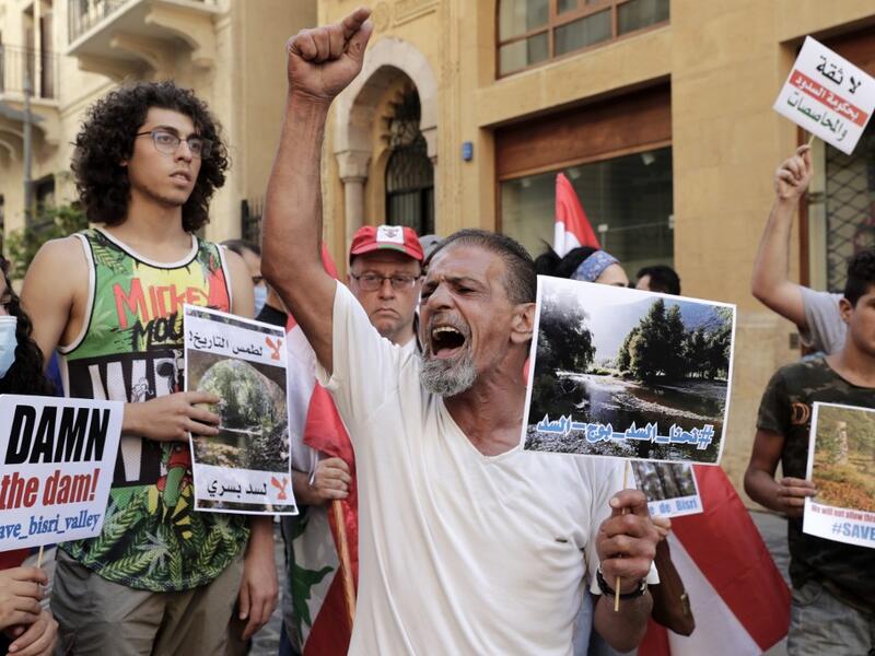 Demonstrators hold placards as they take part in a rally in front of the World Bank offices in the downtown district of the Lebanese capital Beirut on July 25, 2020, to protest against the Bisri dam project, partly financed by the World Bank. The government says the Bisri dam is vital to tackling chronic water shortages. But activists say it will ravage most of the region's farmland and historic sites, and they also fear the consequences of building it on a seismic fault line.  ANWAR AMRO / AFP