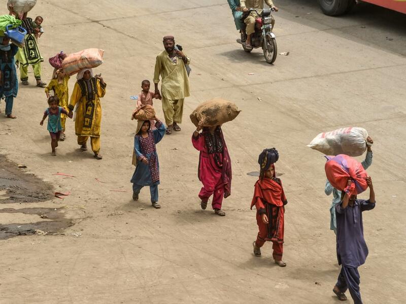 People carrying their belongings arrive at a bus station to go back home ahead of the Muslim festival Eid al-Adha or the 'Festival of Sacrifice' at a bus station in Lahore on July 30, 2020.  Arif ALI / AFP