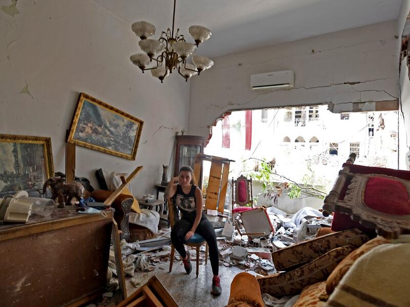 A woman sits amidst the rubble in her damaged house in the Lebanese capital Beirut on August 6, 2020, two days after a massive explosion shook the Lebanese capital. The blast, which appeared to have been caused by a fire igniting 2,750 tonnes of ammonium nitrate left unsecured in a warehouse, was felt as far away as Cyprus, some 150 miles (240 kilometres) to the northwest. The scale of the destruction was such that the Lebanese capital resembled the scene of an earthquake, with thousands of people left home