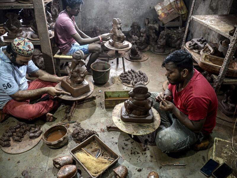 In this picture taken on August 15, 2020, Muslim potter Yusuf Zakaria Galwani (L) along with his staff, work on the idols of elephant headed Hindu god Ganesha at his workshop at Kumbharwada inside the Dharavi slums in Mumbai. After the coronavirus pandemic clobbered his pottery business, a Muslim artisan from India's largest slum turned to a Hindu god to revive his fortunes by making environmentally-friendly Ganesha idols for an upcoming festival. In Mumbai's Dharavi slum, Galwani worked alongside his two b