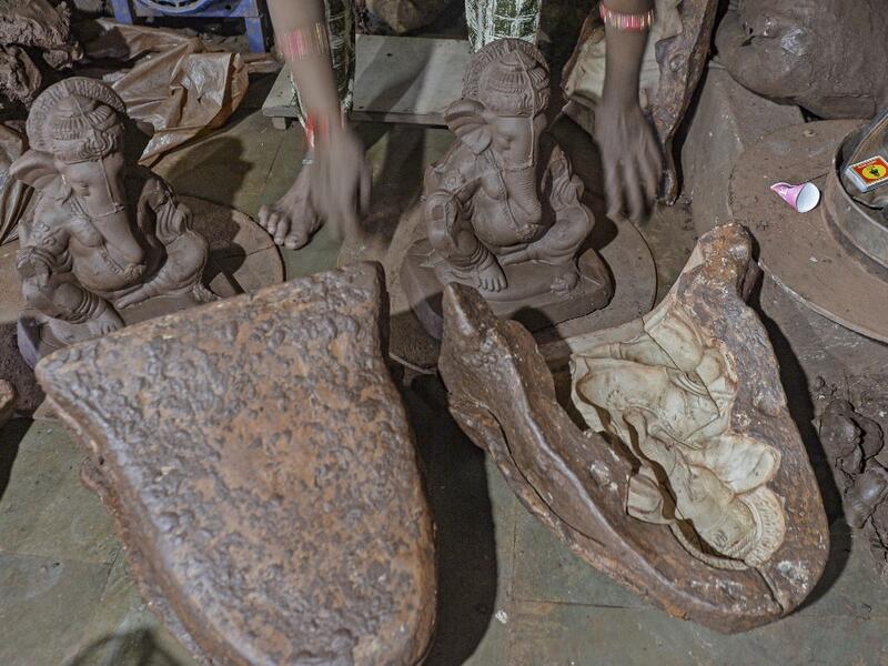 In this picture taken on August 15, 2020, a staff takes out a clay idol of elephant headed Hindu god Ganesha from a mould at Muslim potter Yusuf Zakaria Galwani's workshop at Kumbharwada inside the Dharavi slums in Mumbai. After the coronavirus pandemic clobbered his pottery business, a Muslim artisan from India's largest slum turned to a Hindu god to revive his fortunes by making environmentally-friendly Ganesha idols for an upcoming festival. In Mumbai's Dharavi slum, Galwani worked alongside his two brot
