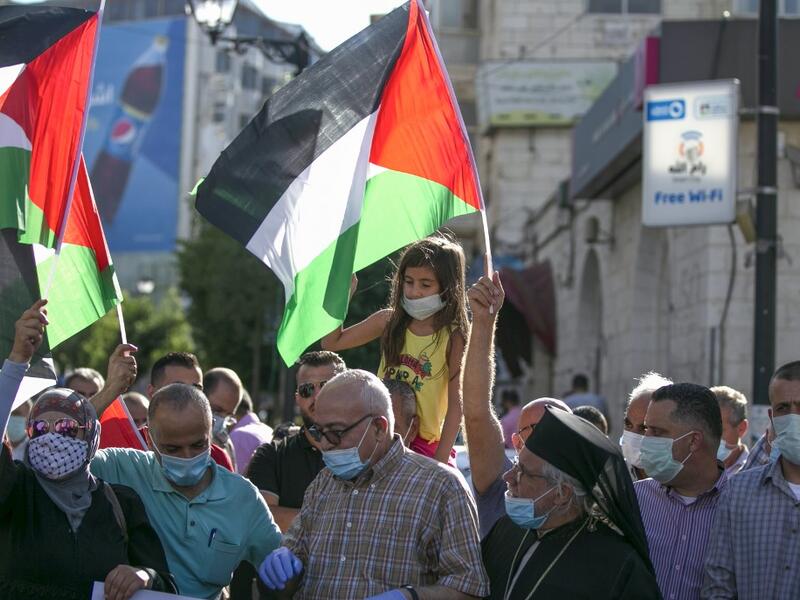 Palestinian protesters lift national flags during a demonstration against the Emirati-Israeli agreement, in Ramallah in the occupied West Bank, on August 15, 2020. ABBAS MOMANI / AFP