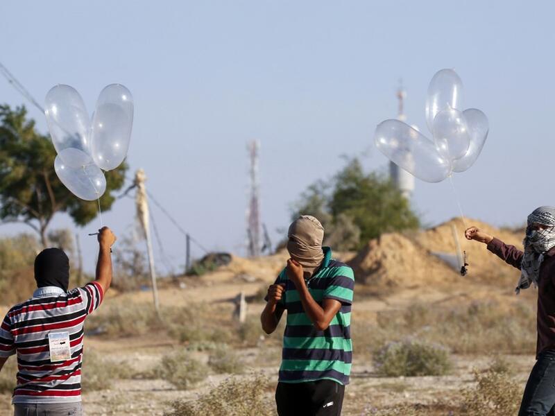 Palestinians prepare incendiary devices attached to inflated condoms to be directed and flown towards Israel, near Rafah along the border between the Gaza Strip and Israel on August 21, 2020. SAID KHATIB / AFP