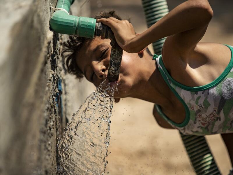 A Syrian boy drinks from the faucet of a water cistern provided by humanitarian organisations during a water outage in Syria's northeastern city of Hasakah on August 22, 2020. As coronavirus spreads across northeast Syria, residents in Hasakeh have been caught up in the latest spat between Turkish forces to the north and Syrian Kurds it views as "terrorists". In October last year, Turkish forces occupied a 120-stretch (70-mile) stretch of land inside the Syrian border, including the Alouk power station that