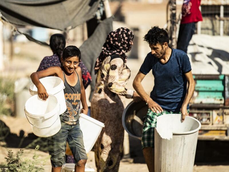 Residents carry plastic buckets to fill up water from cisterns, provided by humanitarian organisations, during a water outage in Syria's northeastern city of Hasakah on August 22, 2020. As coronavirus spreads across northeast Syria, residents in Hasakeh have been caught up in the latest spat between Turkish forces to the north and Syrian Kurds it views as "terrorists". In October last year, Turkish forces occupied a 120-stretch (70-mile) stretch of land inside the Syrian border, including the Alouk power st