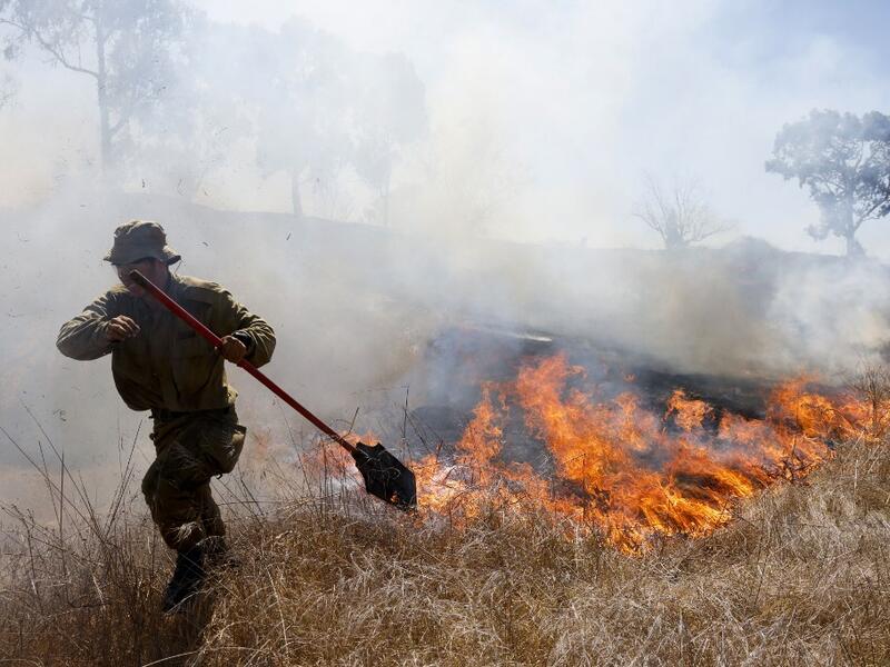 An Israeli soldier battles a blaze in a field close to the southern Israeli kibbutz of Nir Am near the border with the Gaza Strip on August 23, 2020, after it was reportedly set off by incendiary kites flown from the Palestinian enclave. menahem kahana / AFP