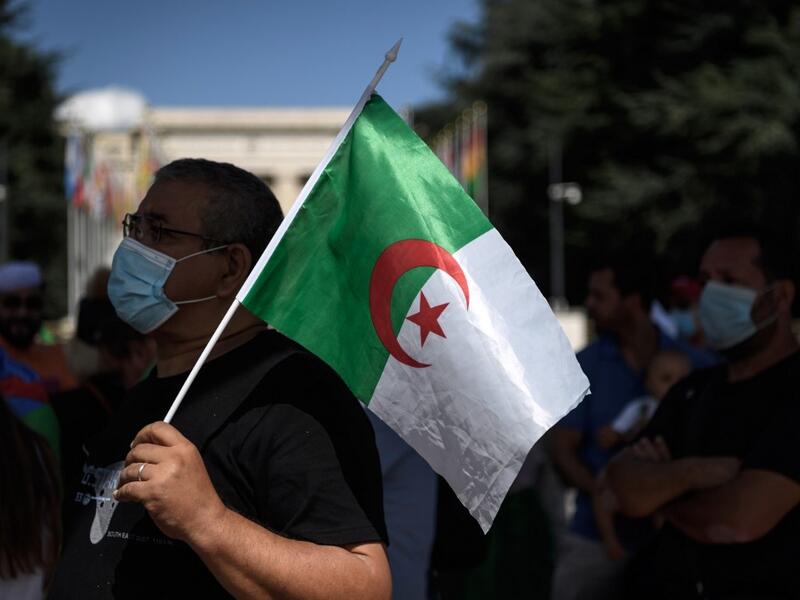 A man wearing a protective mask holds an Algerian flag during a demonstration in front of the United Nations Offices in Geneva against "arbitrary arrests" in Algeria, on August 23, 2020. Fabrice COFFRINI / AFP
