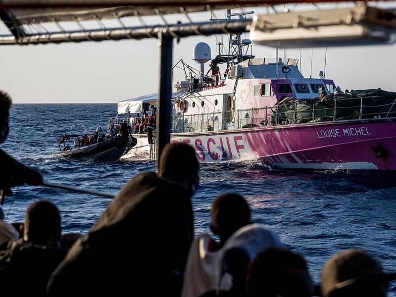 Migrants rescued by Sea-Watch 4 a week ago in the international waters off Libya watch crew members of civil sea rescue ship Sea-Watch 4 on inflatable boats help migrants to get off the rescue ship (AFP)