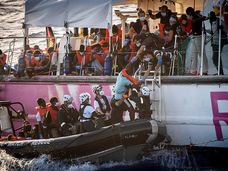 Crew members of civil sea rescue ship Sea-Watch 4 and medical Doctors Without Borders (MSF) on inflatable boats help migrants to get off the rescue ship (AFP)