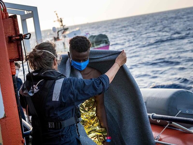 Civil sea rescue ship Sea-Watch 4 crew and Doctors without Borders members help migrants and cover them with blankets  (AFP)
