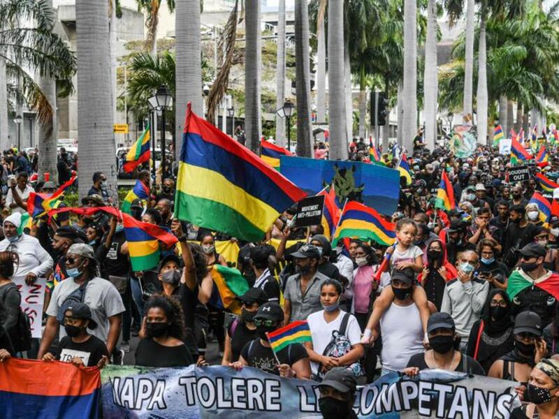 People hold up national flags as they protest against the government's response to the oil spill disaster that happened in early August near the prime minister's office in Port Louis, Mauritius, August 29, 2020. (AFP)