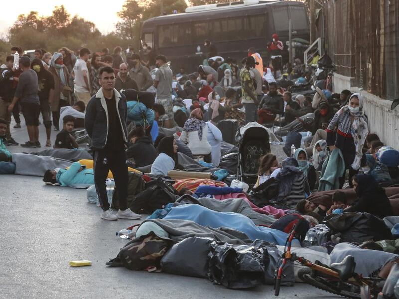 People stand in a street on the island of Lesbos after a major fire broke out in the camp of Moria, on September 9, 2020. Thousands of asylum seekers on the Greek island of Lesbos fled for their lives on September 9, 2020 as a huge fire ripped through the camp of Moria, the country's largest and most notorious migrant facility. 