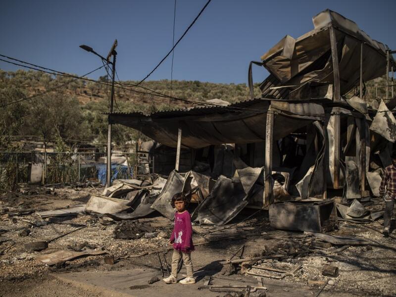 A girl stands amid rubbles in the burnt camp of Moria on the island of Lesbos after a major fire broke out, on September 9, 2020. Thousands of asylum seekers on the Greek island of Lesbos fled for their lives on September 9, 2020 as a huge fire ripped through the camp of Moria, the country's largest and most notorious migrant facility. Over 12,000 men, women and children ran in panic out of containers and tents and into adjoining olive groves and fields as the fire destroyed most of the overcrowded, squalid