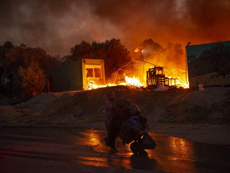 A man carrying belongings flees flames after a major fire broke out in the Moria migrants camp on the Greek Aegean island of Lesbos, on September 9, 2020.