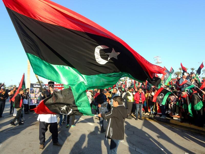 In this file photo taken on February 17, 2020, Libyans wave the national flag as they commemorate the ninth anniversary of the uprising against former Libyan leader Moamer Kadhafi, in Tripoli on February 17, 2020. Mahmud TURKIA / AFP