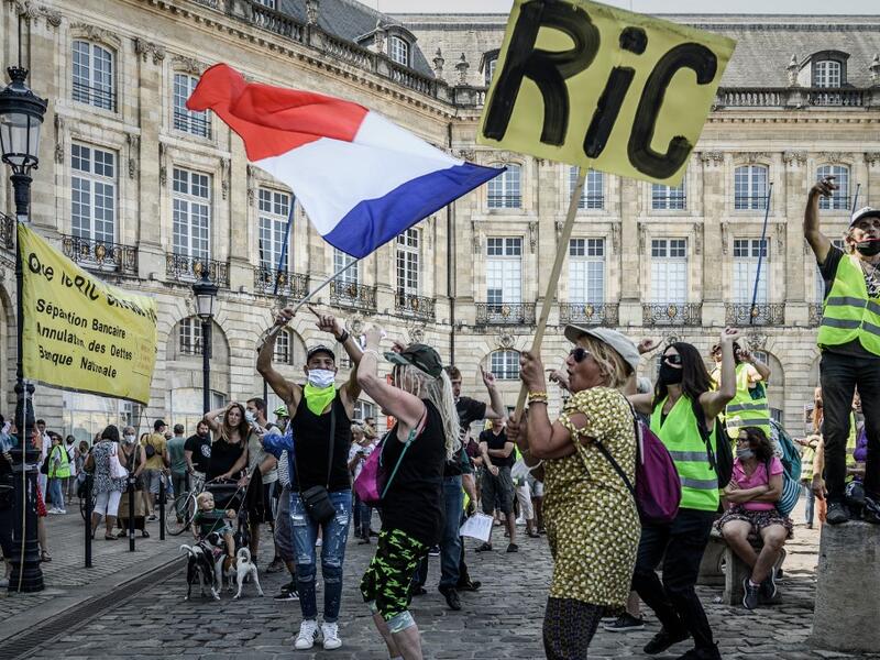 A protester holds a sign reading "RIC" for "Citizens Initiative Referendum" and another wave a French national flag as they take part in a demonstration called by the "Yellow Vest" (Gilets Jaunes) movement in Bordeaux, southwestern France on September 12, 2020. Philippe LOPEZ / AFP