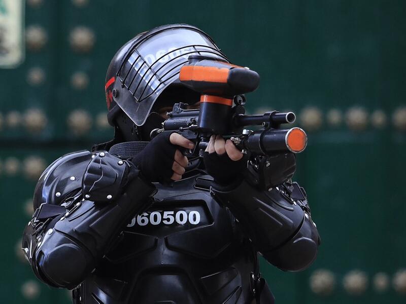 A riot police officer points his gun towards protestors during the fifth straight day of protests against police brutality in Bogota on September 13, 2020. Bogota's Mayor Claudia Lopez, apologized this Sunday for the abuses of the public force, in a ceremony that gathered relatives of the dead and wounded during the bloody protests that broke out five days ago against police brutality in Colombia. DANIEL MUNOZ / AFP