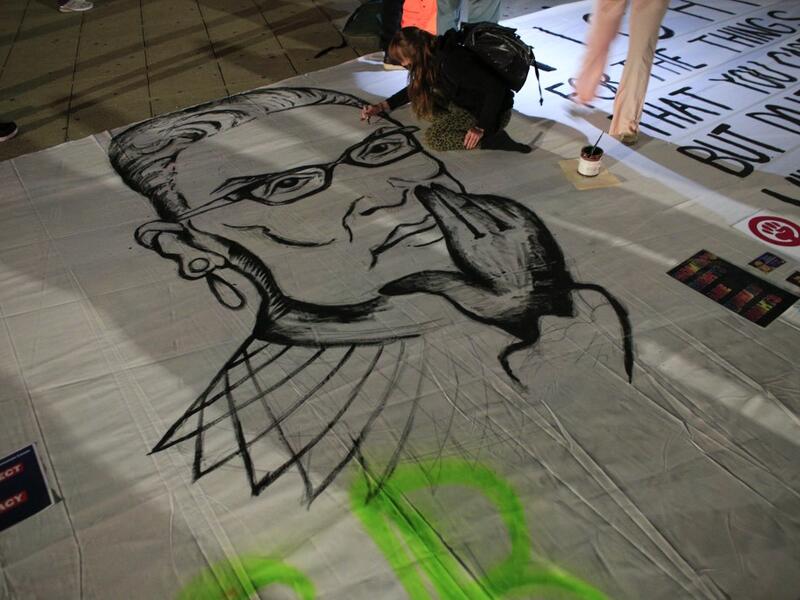 A woman paints an image of Ruth Bader Ginsburg as people pay their respects to her outside of the New York State Civil Supreme Court building in New York on September 19, 2020. US President Donald Trump vowed to quickly nominate a successor, likely a woman, to replace late Supreme Court Justice Ruth Bader Ginsburg, only a day after the death of the liberal stalwart. Kena Betancur / AFP