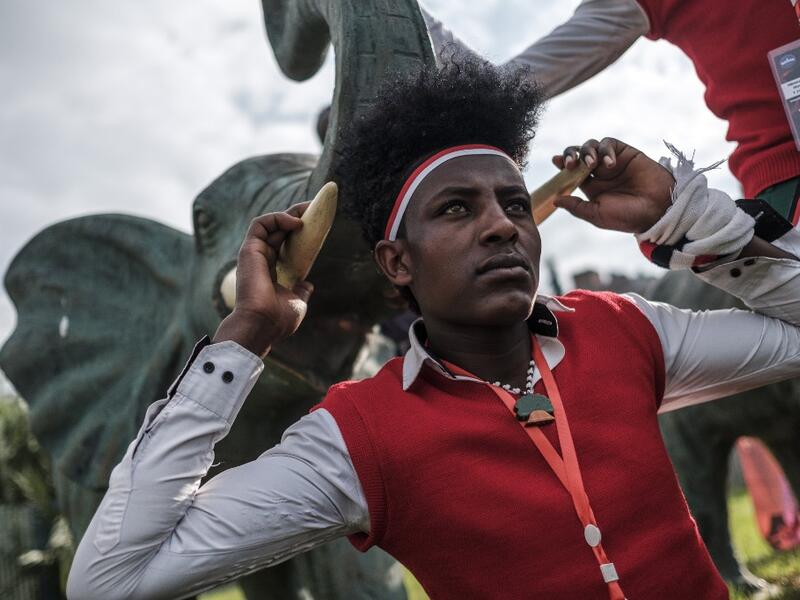 A young man in traditional clothing pose for a picture next to the statue of an elephant during the celebration of “Irreechaa”, the Oromo people thanksgiving holiday, in Addis Ababa, Ethiopia, on October 3, 2020. EDUARDO SOTERAS / AFP