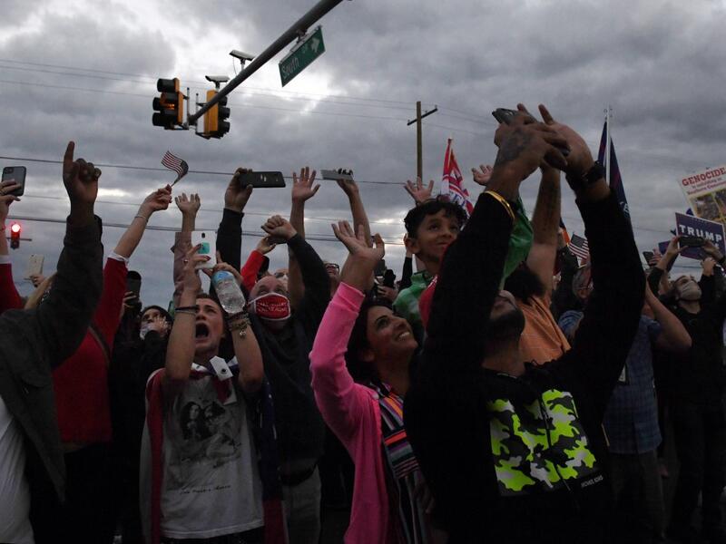 Supporters cheer as Marine One carrying the US President leaves Walter Reed Medical Center in Bethesda, Maryland on October 5, 2020, to return to the White House after the president was discharged. Trump announced Monday he would be "back on the campaign trail soon", just before returning to the White House from a hospital where he was being treated for Covid-19. Olivier DOULIERY / AFP