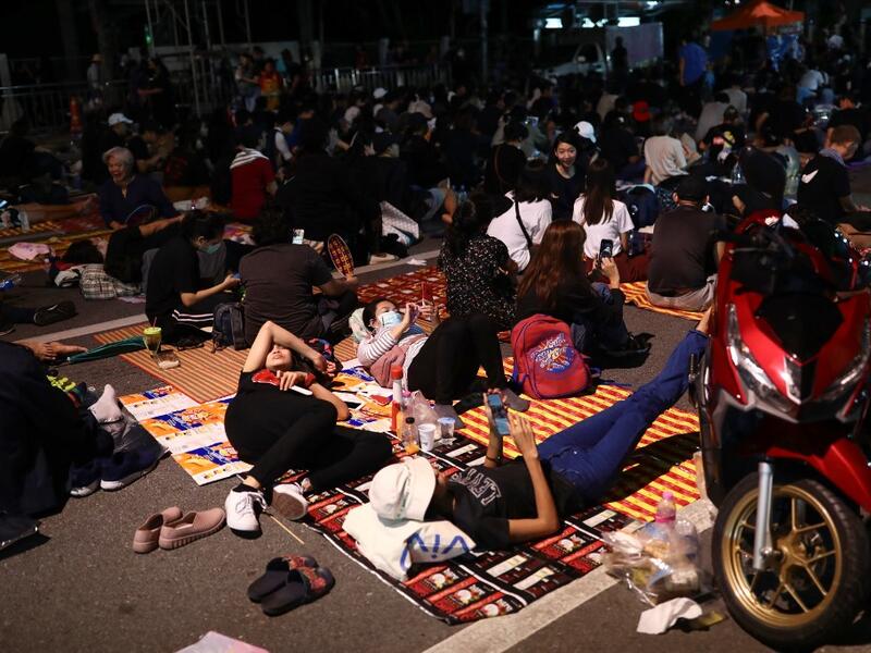 Pro-democracy protesters rest on the ground during an anti-government rally next to Government House in Bangkok on October 14, 2020. Jack TAYLOR / AFP