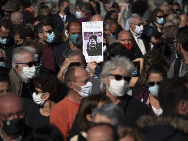 A person holds the front page of French satirical weekly Charlie Hebdo reading "Liberty, tolerance and equality" as people gather on the Vieux Port in Marseille on October 18, 2020, in homage to history teacher Samuel Paty two days after he was beheaded by an attacker who was shot dead by policemen. CHRISTOPHE SIMON / AFP