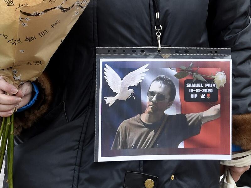 A woman holds a picture of Samuel Paty, Place de la Liberte in Lille on October 18, 2020, in homage to the history teacher, two days after he was beheaded by an attacker who was shot dead by policemen. FRANCOIS LO PRESTI / AFP