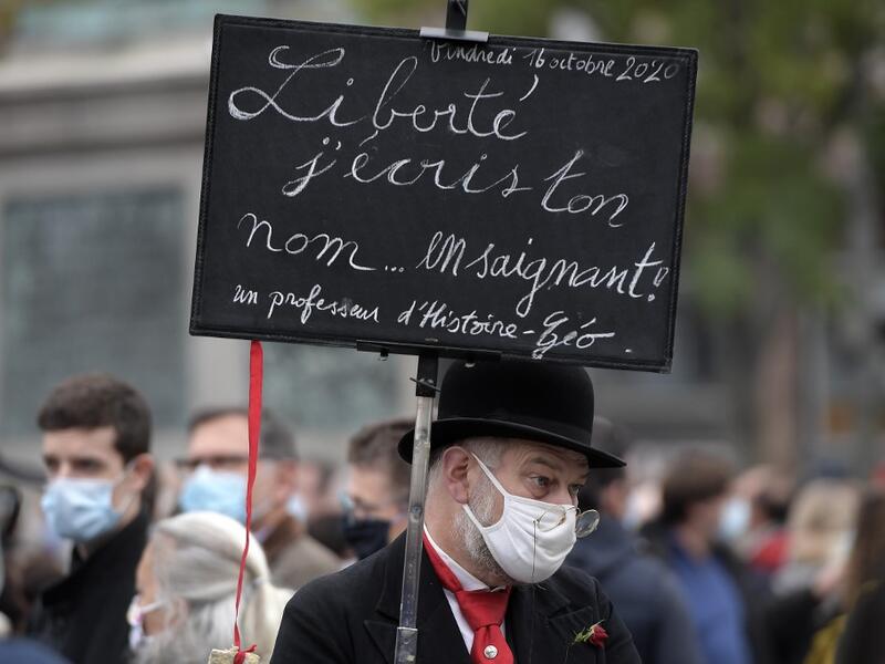 A man holds a placard reading "Liberty, I write your name by bleeding" as people gather in Strasbourg, eastern France, on October 18, 2020, in homage to history teacher Samuel Paty two days after he was beheaded by an attacker who was shot dead by policemen. FREDERICK FLORIN / AFP
