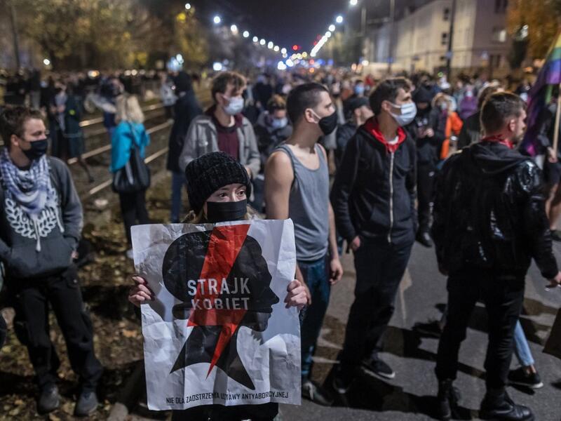 A woman holds a banner reading "Strajk Kobiet" (Women's Strike) in front of the house of Jaroslaw Kaczynski, leader of Poland's ruling Law and Justice party (PIS), during a demonstration against a decision by the Constitutional Court on abortion law restriction, Warsaw, October 23, 2020, in Warsaw on October 23, 2020. Wojtek RADWANSKI / AFP