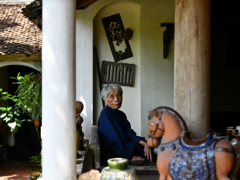This photograph taken on October 8, 2020 shows 89-year-old Vietnamese artist Mong Bich posing at her house in Bac Ninh province, east of Hanoi. Bich specialises in silk paintings of daily life and ordinary people, women in particular, and ploughed a lonely furrow during many years of war when artists were steered towards the army or frontline workers as subjects. Manan VATSYAYANA / AFP