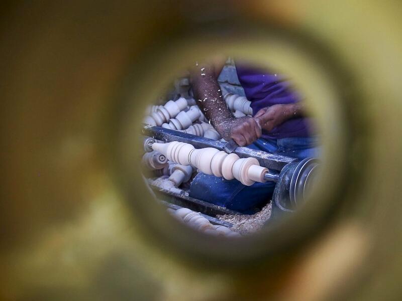 A carpenter shaves a piece of wood to make a narguileh (water pipe) at his workshop in Iraq's central holy city of Karbala on October 21, 2020. The business of strictly gender-separated cafes has carried on, despite the heavy health risks associated with smoking and a full-blown pandemic that has brought an average of 4,000 new coronavirus cases a day to Iraq. Mohammed SAWAF / AFP