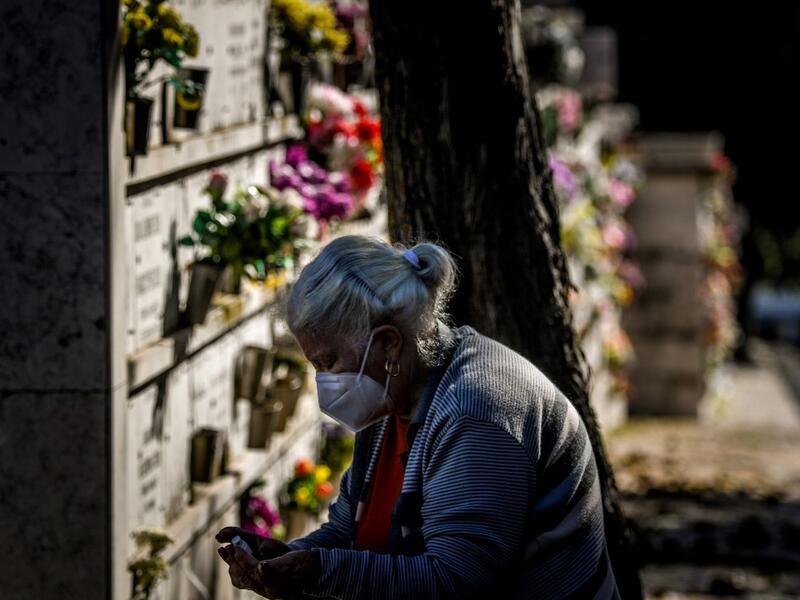 A woman wearing a face mask disinfects her hands at the Alto de Sao Joao cemetery in Lisbon on October 30, 2020 on the eve of All Saints' Day amid the coronavirus pandemic. PATRICIA DE MELO MOREIRA / AFP