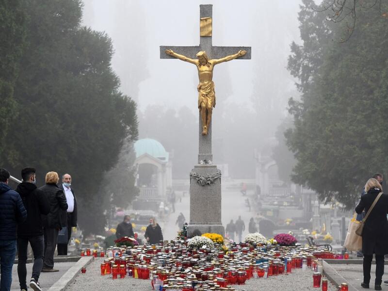 Faithfuls gather near the central cross, where candles have been laid, at the Mirogoj Cemetery in Zagreb, on November 1, 2020 to mark All Saints' Day. Every year on All Saints' Day, Croatian citizens visit and arrange the graves of their families. This year, due to the coronavirus pandemic, the usual crowds in cemeteries were absent, as citizens heeded the recommendation of the authorities to avoid mass gatherings. DENIS LOVROVIC / AFP