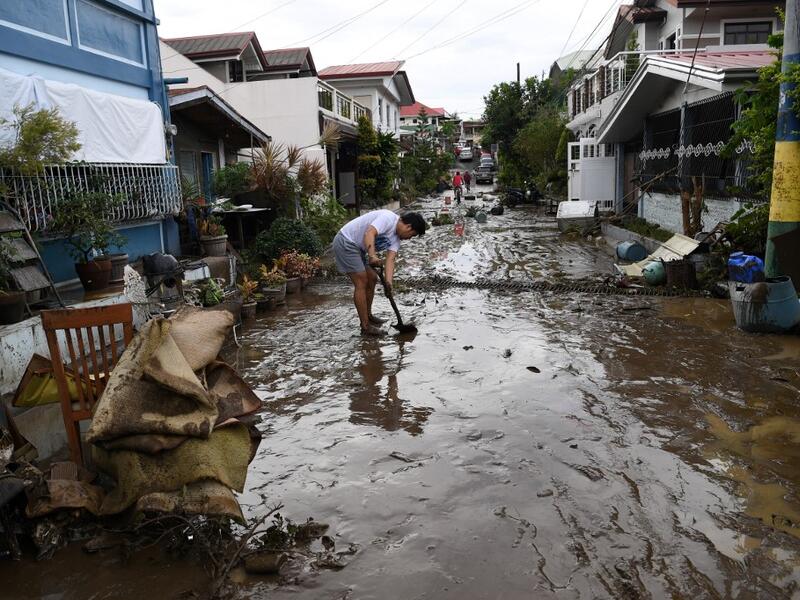 A resident shovels mud from a neighbourhood street following flooding in Batangas City on November 2, 2020, after super Typhoon Goni made landfall in the Philippines on November 1. TED ALJIBE / AFP