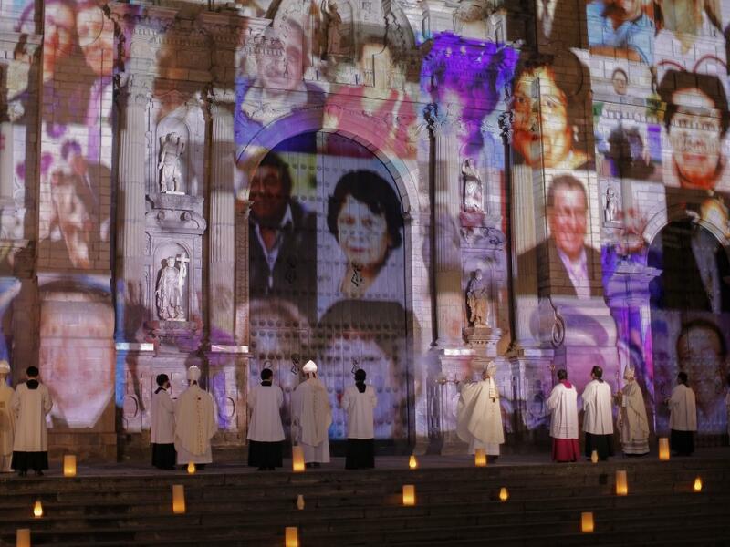 View of COVID-19 victims pictures proyected on the Lima Cathedral during a candlelight open-air mass with no public at the Plaza de Armas Main Square, in Lima on November 1, 2020 in remembrance of the more than 34,000 deceased from the coronavirus pandemic in Peru. The mass was conducted during the commemoration of the All Saints' Day under the projected images of elderly, children, firefighters, nurses, policemen, military victims of COVID-19 in Peru. Since the pandemic arrived in marchs to the country mor