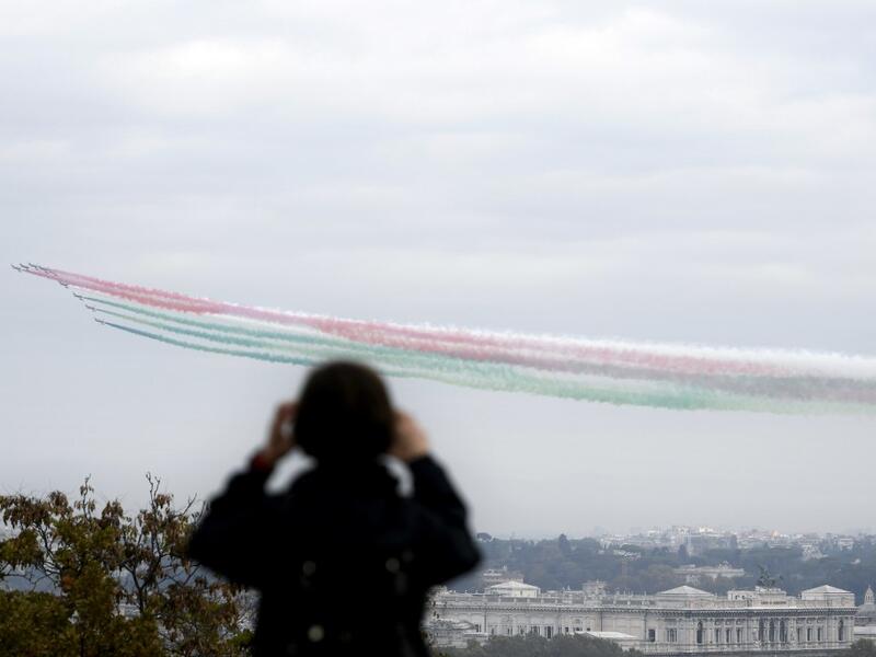 An onlooker takes a picture of the jets of the Italian Air Force aerobatic unit Frecce Tricolori (Tricolor Arrows) spreading smoke with the colors of the Italian flag as they fly over the city of Rome during the Armed Forces Day marking the end of World War I for Italy, on November 4, 2020. Filippo MONTEFORTE / AFP