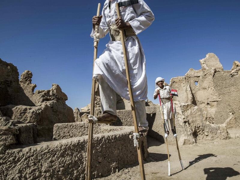 Egyptian school children dressed in traditional outfits, walk with stilts during a celebration to mark the inauguration of the fortress of Shali following its restoration, in the Egyptian desert oasis of Siwa, some 600 kms southwest of the capital Cairo, on November 6, 2020. Khaled DESOUKI / AFP