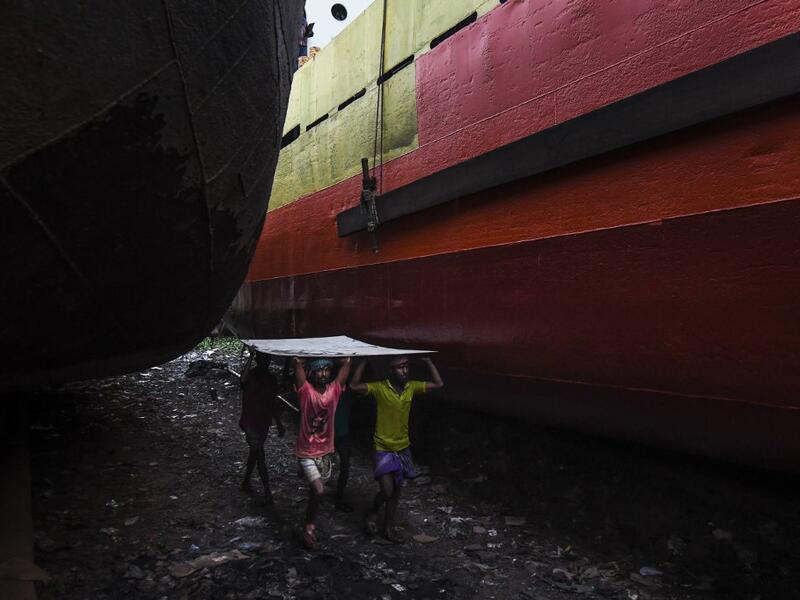 In this picture taken on November 16, 2020 dockyard workers carry a metal sheet during maintenance works for a ship on the banks of the Buriganga River in Char Kaliganj on the outskirts of Dhaka. Rivers are the lifeblood of the delta nation of 168 million people where much of the low-lying land is accessed via boat, with Bangladesh's strong economic growth of recent years fuelling more investments in new and bigger ships. Munir UZ ZAMAN / AFP