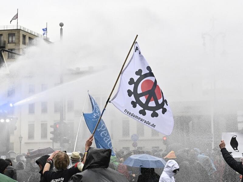 Police use a water cannon to disperse protesters demonstrating against measures imposed by the German government to limit the spread of the novel coronavirus, on November 18, 2020 at the Brandenburg Gate in Berlin. After repeated warnings for the crowd to put on face coverings went unheeded, police said they would take action to clear the protest and "detain violators". Around 5,000 activists massed at the Brandenburg Gate, after the German government banned rallies outside parliament because of fears of vi