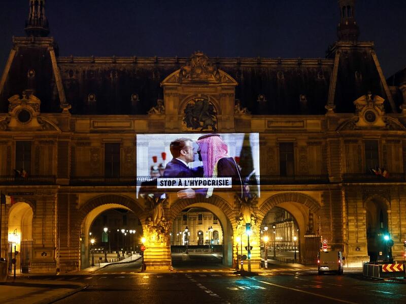 This picture taken early on November 19, 2020, shows a projection on the Louvre Museum in Paris by Amnesty International members depicting French President Emmanuel Macron greeting Saudi Crown Prince Mohammed bin Salman and reading "Stop hypocrisy", ahead of the upcoming virtual G20 summit. THOMAS COEX / AFP