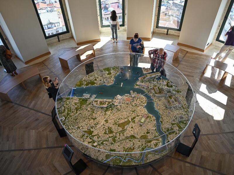 People look at a 3D Istanbul map after the restoration of the Galata Tower on October 16, 2020 in Istanbul. The Galata Tower -- an emblematic 14th century monument of Istanbul -- has become the latest victim of such controversy. The demolition of one of its walls with a jackhammer as part of a restoration work was narrowly avoided last August after a video leaked on social media, which sparked strong criticism from the largest city's residents. Ozan KOSE / AFP
