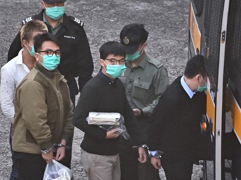 Activists Joshua Wong (C) and Ivan Lam (L) board a police van at Lai Chi Kok Reception Centre in Hong Kong on December 2, 2020, before going to court to be sentenced over a protest which took place outside the police headquarters in 2019. Anthony WALLACE / AFP