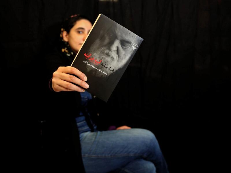 Employee Mahnaz Zabi poses with a bestselling book of the Nashre-Cheshmeh Publishing House in Iran's capital Tehran, on December 5, 2020. ATTA KENARE / AFP