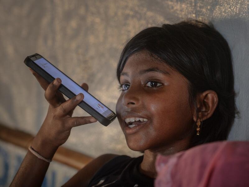In this photograph taken on October 8, 2020, the daughter of Rohingya refugee Arofa Khatun, who tried to migrate with her two daughters to Malaysia to her husband, speaks on the phone with her father at a makeshift shelter in Kutupalong refugee camp in Ukhia. Stay in a squalid refugee camp -- hopeless, starving, and made to feel a burden -- or leave, risking death, rape, human trafficking and months at sea to reach a husband you've never met. This is the bleak choice many Rohingya women, already scarred fro