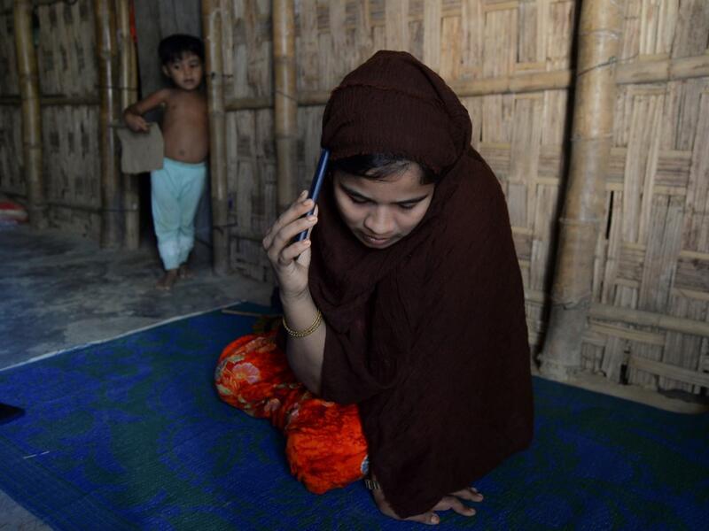 In this photograph taken on October 13, 2020, Rohingya refugee Umme Khair, who gave money to a community leader to travel to Malaysia to her husband, speaks on her mobile phone at a makeshift shelter in Kutupalong Rohingya refugee in Ukhia. Stay in a squalid refugee camp -- hopeless, starving, and made to feel a burden -- or leave, risking death, rape, human trafficking and months at sea to reach a husband you've never met. This is the bleak choice many Rohingya women, already scarred from fleeing persecuti
